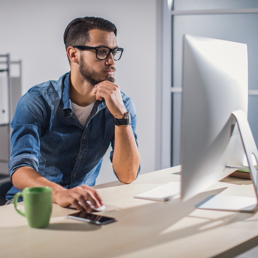 Homme travaillant sur ordinateur pour automatiser sa prospection tout en gardant une touche humaine